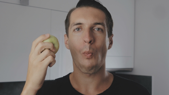 Young Man Eating Green Apple at Home in the Kitchen, Stock Footage