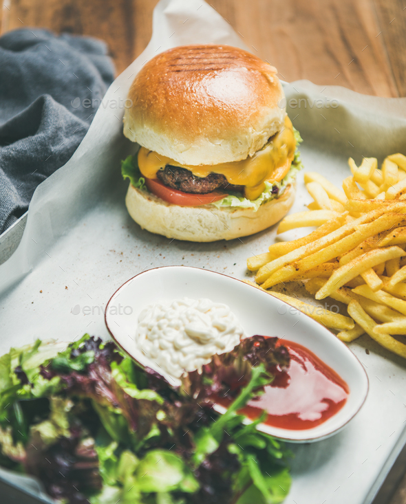 Beef burger, french fries, salad, suaces on tray, selective focus - Stock Photo - Images