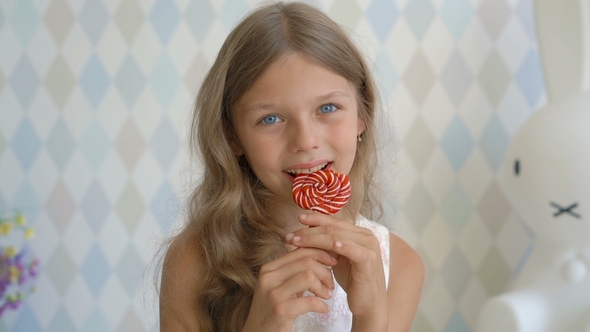 Funny Child with Candy Lollipop, Happy Little Girl Eating Lollipop, Kid Eat Sweets at Home alt