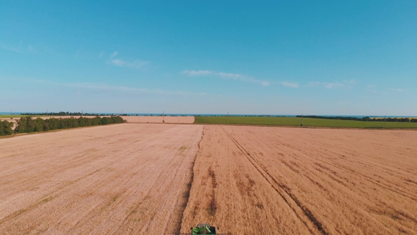 Aerial View of a Combine Harvester Working in a Field at Sunset