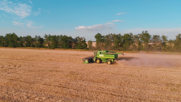 Aerial View of a Combine Harvester Working in a Field at Sunset
