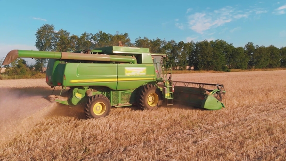 Combine Harvester Working in a Field at sunset