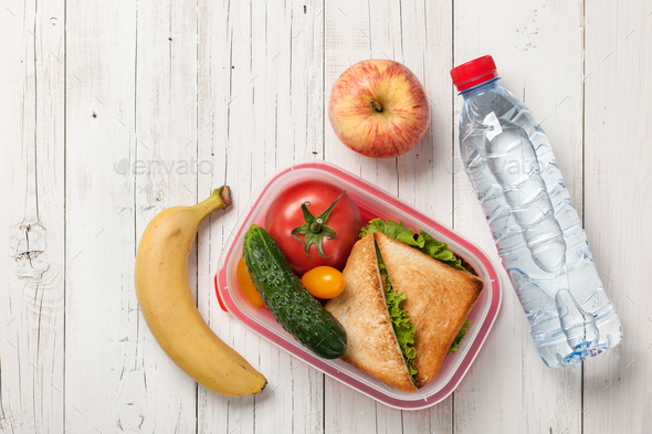 Premium Photo  Lunch box filled with sandwich near two thermos, fresh  apples and oranges, bananas in front of white modern kitchen table