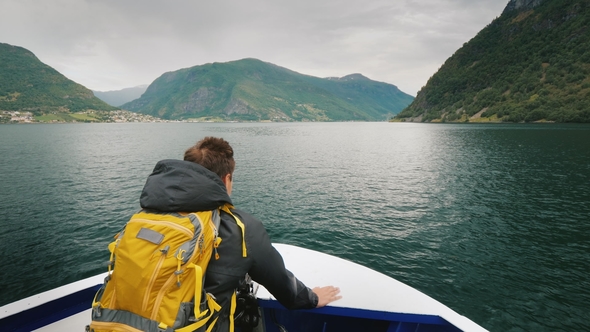 A Man with a Backpack Travels Through a Picturesque Fjord in Norway alt