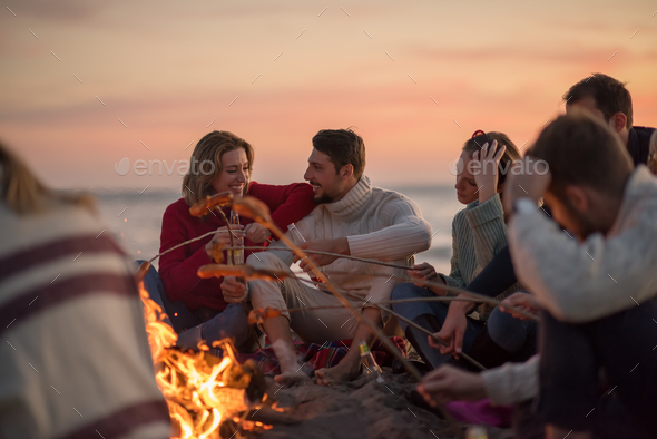 Group Of Young Friends Sitting By The Fire at beach Stock Photo by dotshock
