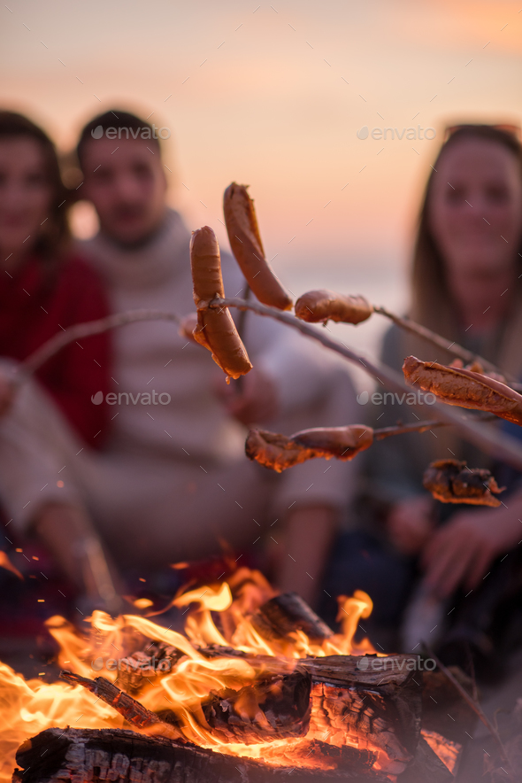 Group Of Young Friends Sitting By The Fire at beach Stock Photo by dotshock