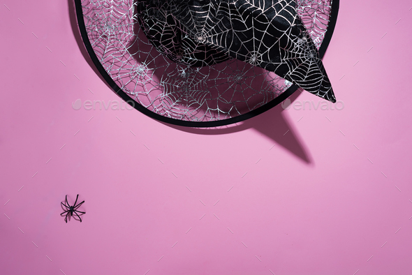 Black witch hat with a pattern of cobwebs and spider on pink background, flat lay with copy space - Stock Photo - Images