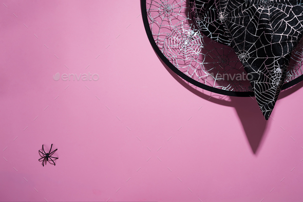 Black witch hat with a pattern of cobwebs and spider on pink background, flat lay with copy space - Stock Photo - Images