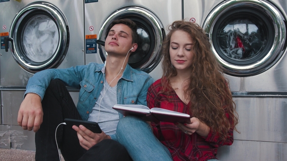 Beautiful Couple in a Laundry Listen To the Music on the Phone, Reading Book, Watching Videos