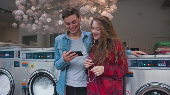 Beautiful Couple in a Laundry Listen To the Music on the Phone, Watching Videos, Stories