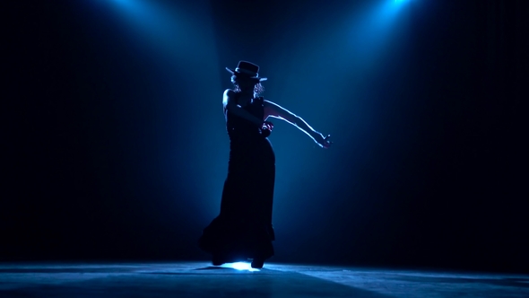 Woman Is Dancing with Castanets in Her Hands Dancing. Llight From Behind. Dark Background alt