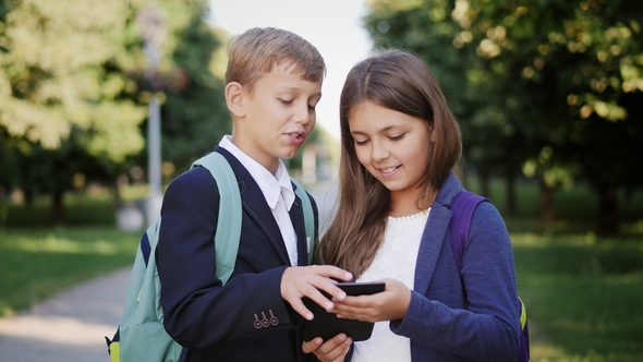 Two Schoolchildren Use a Tablet Outdoors alt