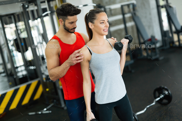 Young adult woman working out in gym with trainer Stock Photo by nd3000
