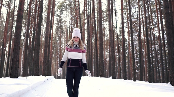 Cheerful Girl Walking Through the Winter Forest and Smiling. Portrait of a Young Woman in a Sweater