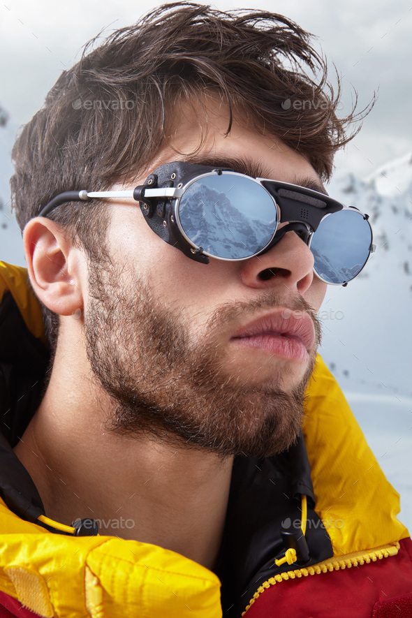 Portrait of mountaineer in winter clothes and ultraviolet protected sunglasses - Stock Photo - Images