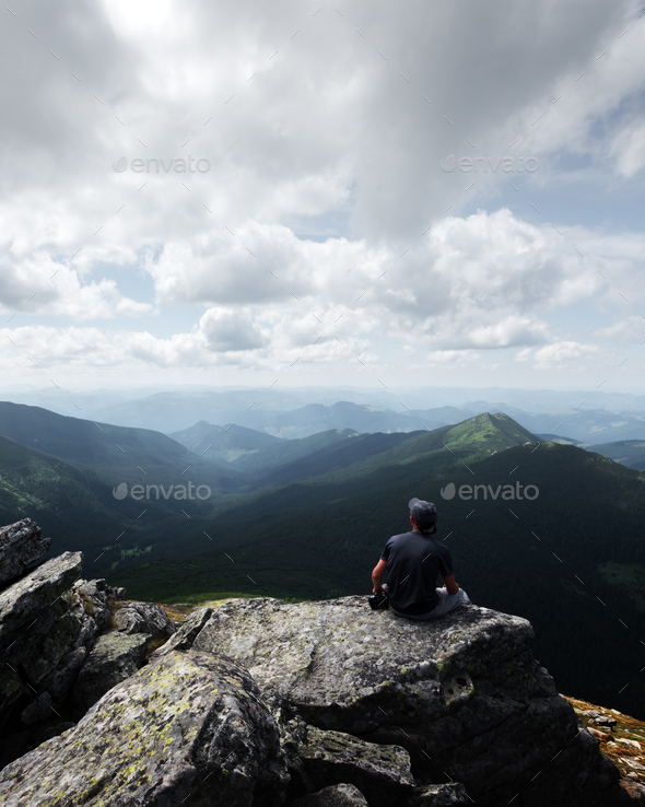 A lone tourist sitting on the edge of the cliff - Stock Photo - Images