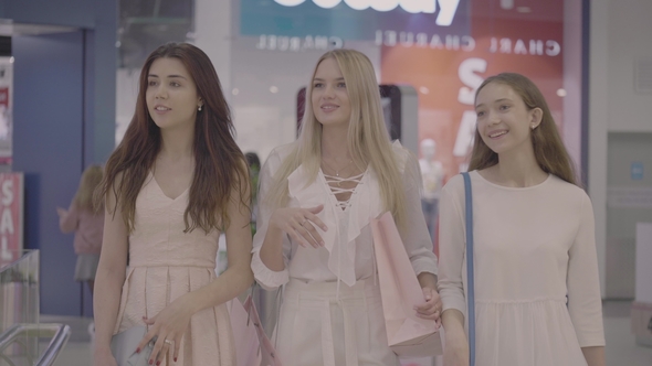 Three Smiling Young Woman Walking in Shopping Mall alt