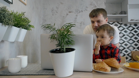 Two Boys and Father Watching Film on the Laptop in the Modern Kitchen