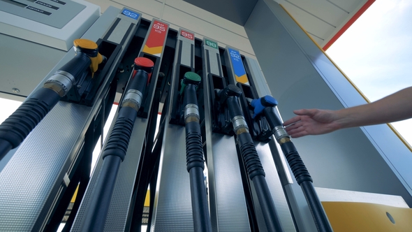 Person at a Gas Station, Bottom View. One Man Takes a Petrol Nozzle at a Gas Station alt