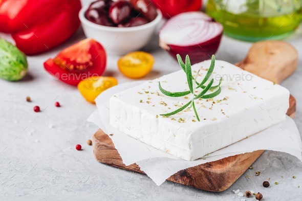 Homemade greek cheese feta with rosemary on wooden cutting board. Ingredients for greek salad Stock Photo by nblxer