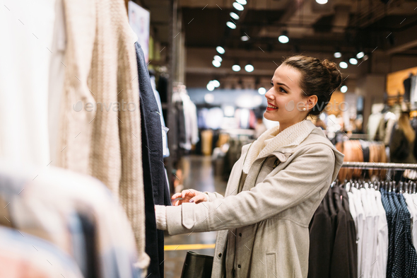 Young attractive woman buying clothes in mall Stock Photo by nd3000