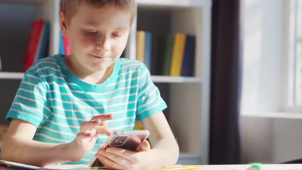 Boy is Doing  Homework at the Table. Cute Child is Learning at Home. alt