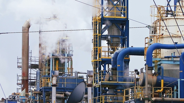 Modern Refinery Complex with Towers and Smoke Against Sky alt