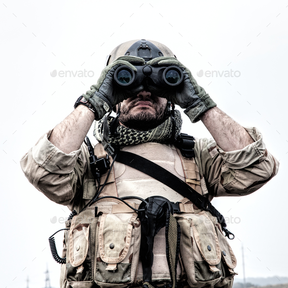 Commando soldier using binoculars to observe terrain - Stock Photo - Images