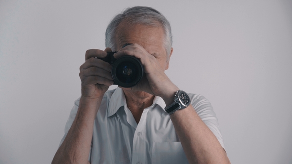 Gray Haired Senior Man Photographer Takes Shots with His Photo Camera at White Background alt