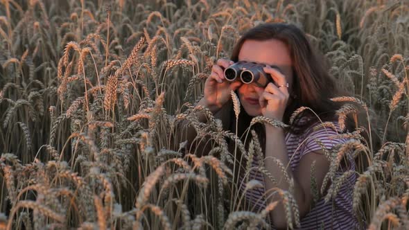 Beautiful Young Girl Looking Through Binoculars On Blue Sky Background. alt