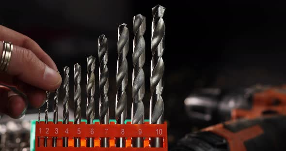 Close up of a metal drill bit set, man take one for work at workshop
