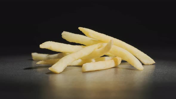 golden French fries rotating on table on black background alt