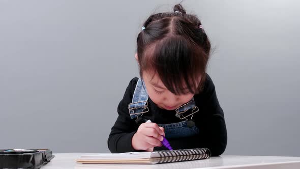 Child choosing black pen in the full case for drawing. Image produced in the studio with a gray back alt