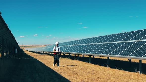 Male Worker Is Walking Along a Solar Power Station alt