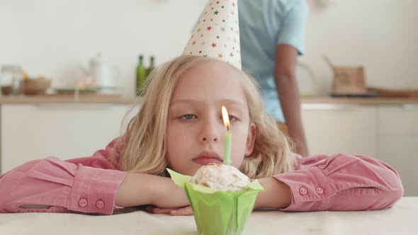 Grumpy Girl Blowing Candle on Muffin alt