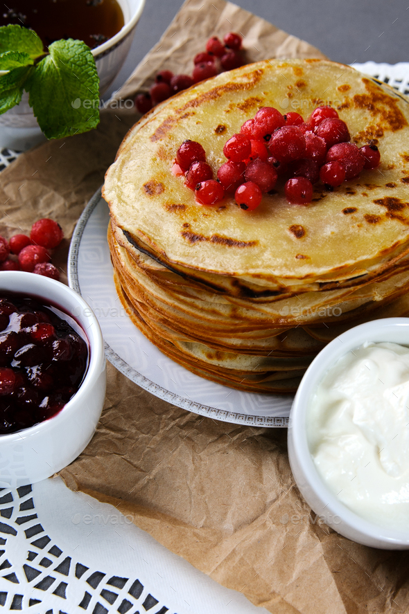Stack of pancakes served with fresh cranberries, jam and cream o - Stock Photo - Images