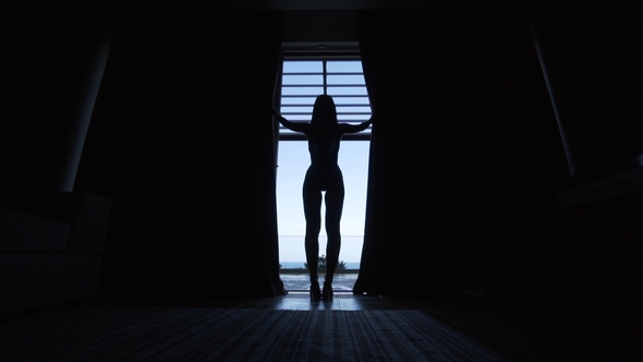 Silhouette Of The Beautiful Girl Opening The Curtains To The Balcony 