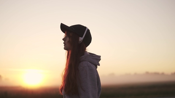 Silhouette of a Girl in Headphones Against the Setting Sun in Nature