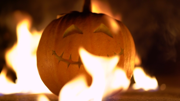Smiling Happy Carved Halloween Pumpkin Against of Fiery Explosion Background. Glowing Face Trick or alt