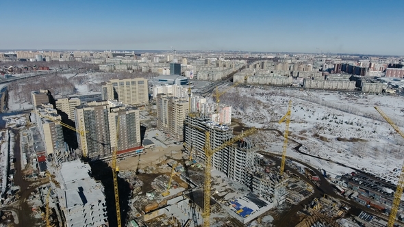 Construction of a New Residential Area in Front of Road Traffic Covered in Snow alt