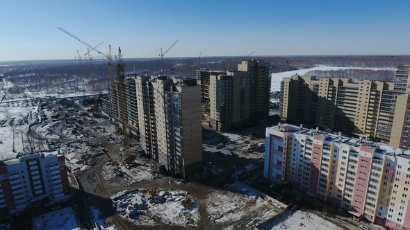 Construction of a New Residential Area in Front of Road Traffic Covered in Snow alt