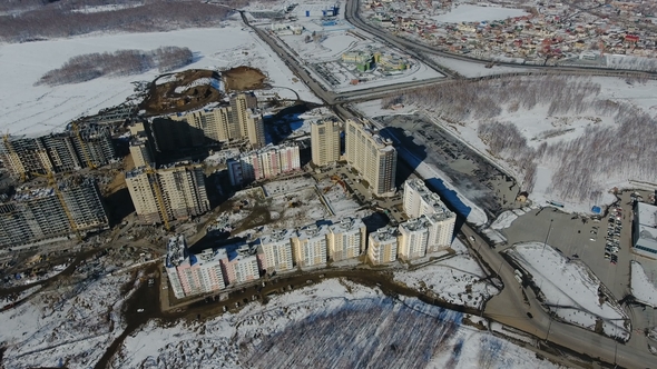 Construction of a New Residential Area in Front of Road Traffic Covered in Snow alt
