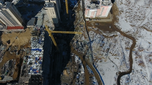 Construction of a New Residential Area in Front of Road Traffic Covered in Snow alt