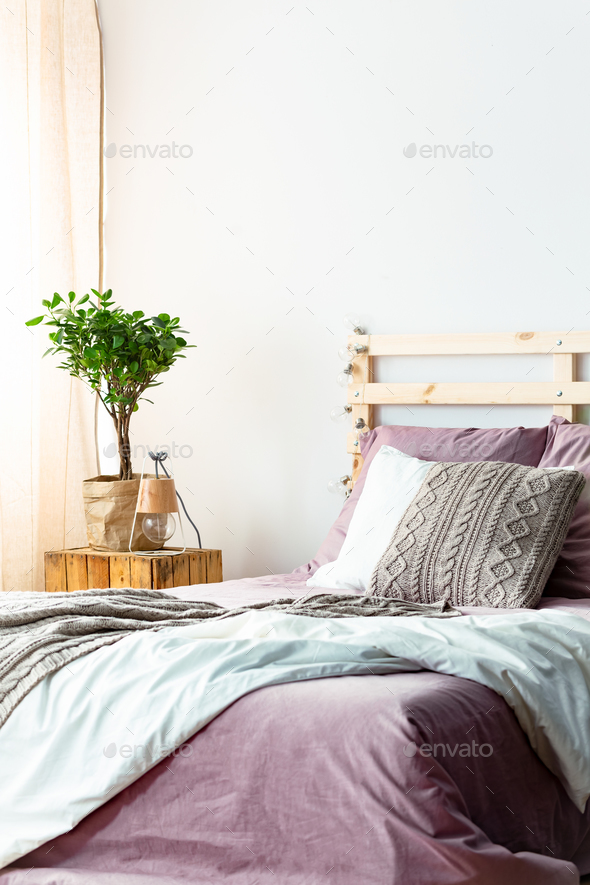 Handmade lamp and fresh plant standing on wooden bedside table n Stock Photo by bialasiewicz