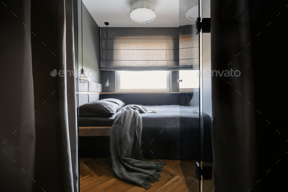 Grey blanket and pillows on bed in simple hotel bedroom interior Stock Photo by bialasiewicz