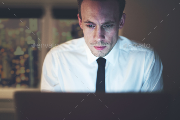 Close up of businessman working overtime on computer Stock Photo by UberImages