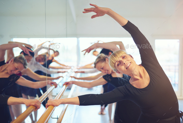 Smiling mature woman stretching in ballet class Smiling mature woman stretching in ballet class