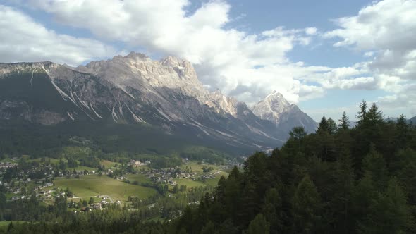 Amazing Aerial Passing Trees Revealing the Italian Dolomites with Small Town in the Foreground alt