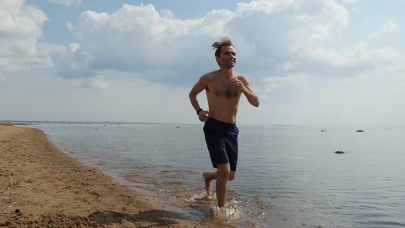 Happy Man Jogging Shirtless on Sandy Beach