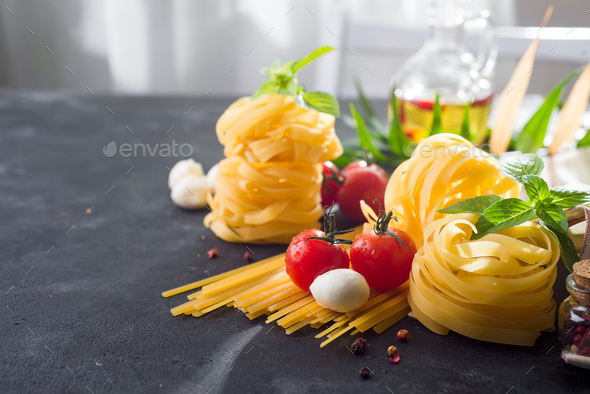 Fettuccine and spaghetti with ingredients for cooking pasta on black stone slate background Stock Photo by lyulkamazur